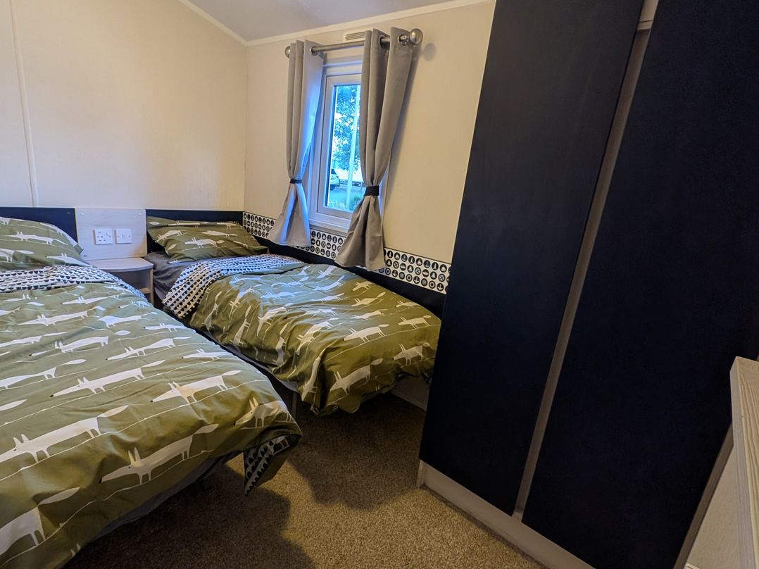 A bedroom with two single beds and a wardrobe at Presthaven - Denbigh Dunes in Gronant
