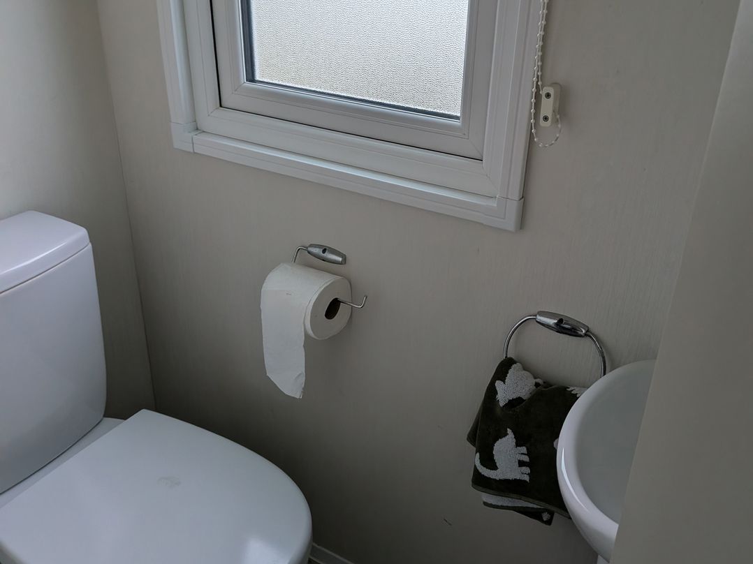 A bathroom with a toilet and window at Presthaven - Denbigh Dunes in Gronant