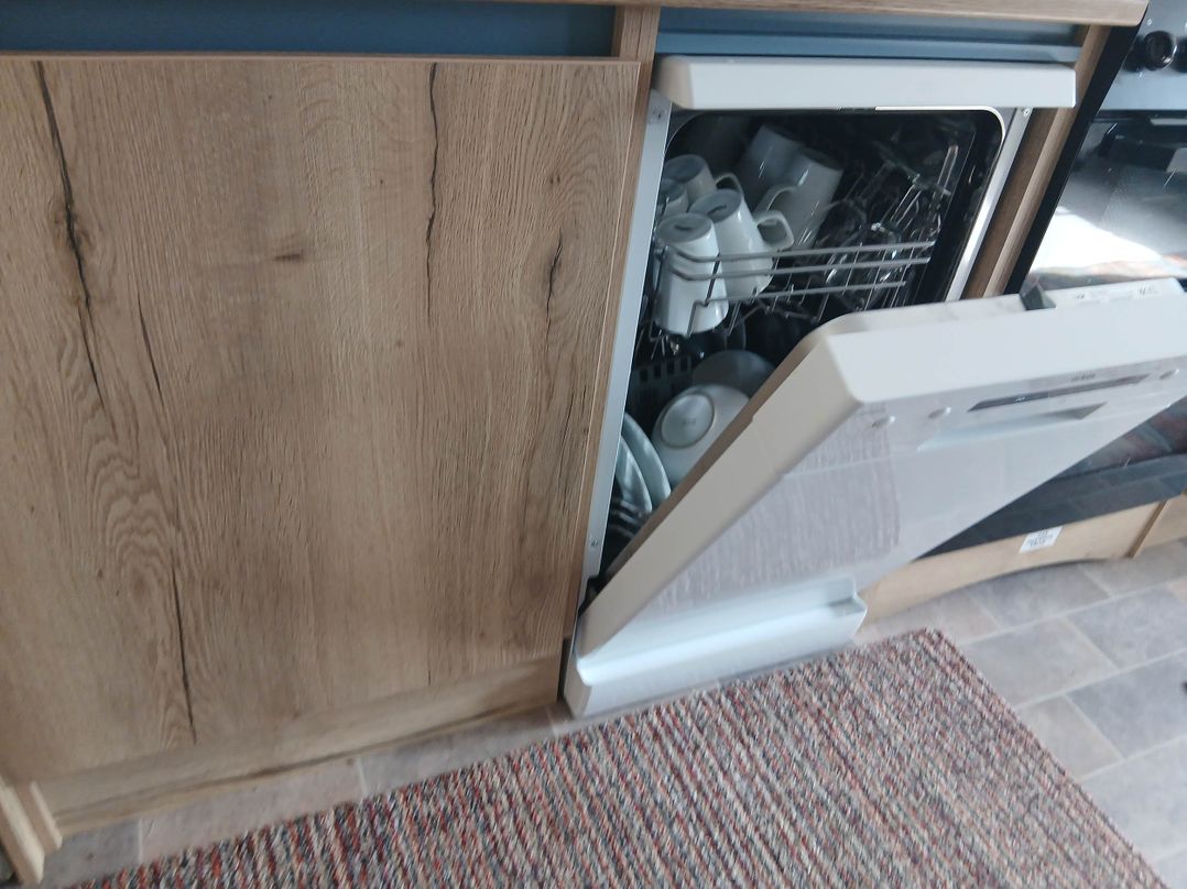 A kitchen with an open dishwasher containing dishes in Porthcurno 5, Perranwell near Goonhavern