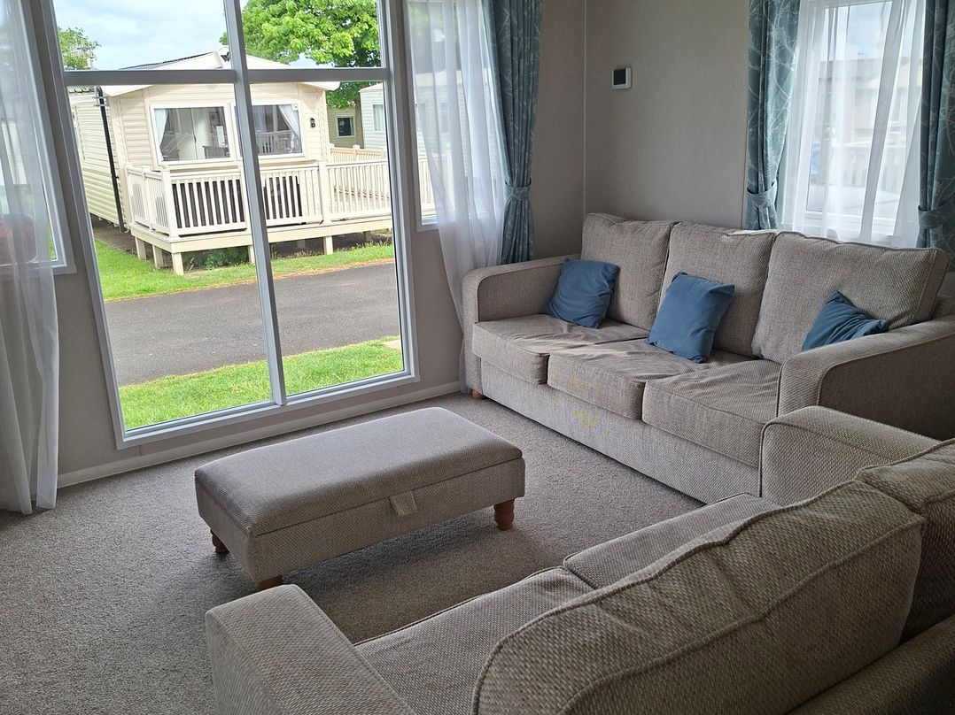 A living room with a sofa and footstool at Primrose Valley, Amara's Retreat in Filey