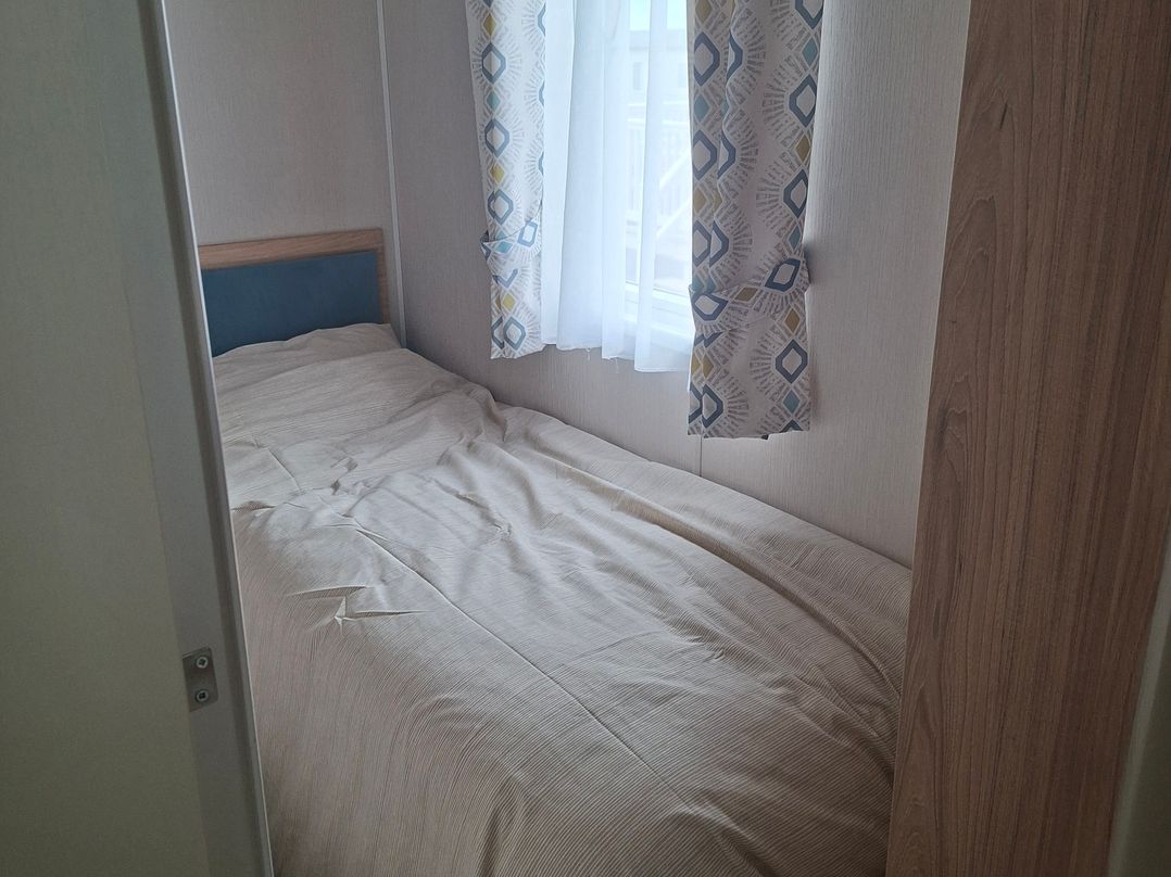 A bedroom with a bed and window at Primrose Valley, Amara's Retreat in Filey