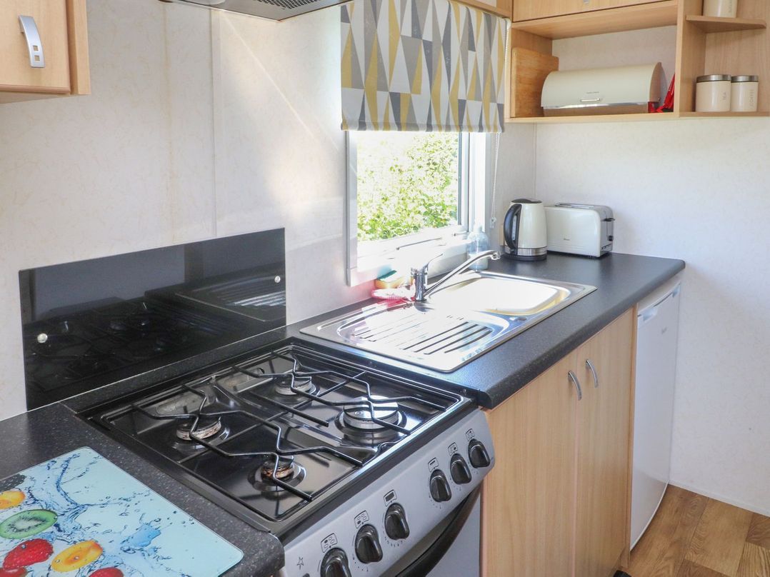 A kitchen with a stove, sink, and kettle at The Lodge in Amlwch