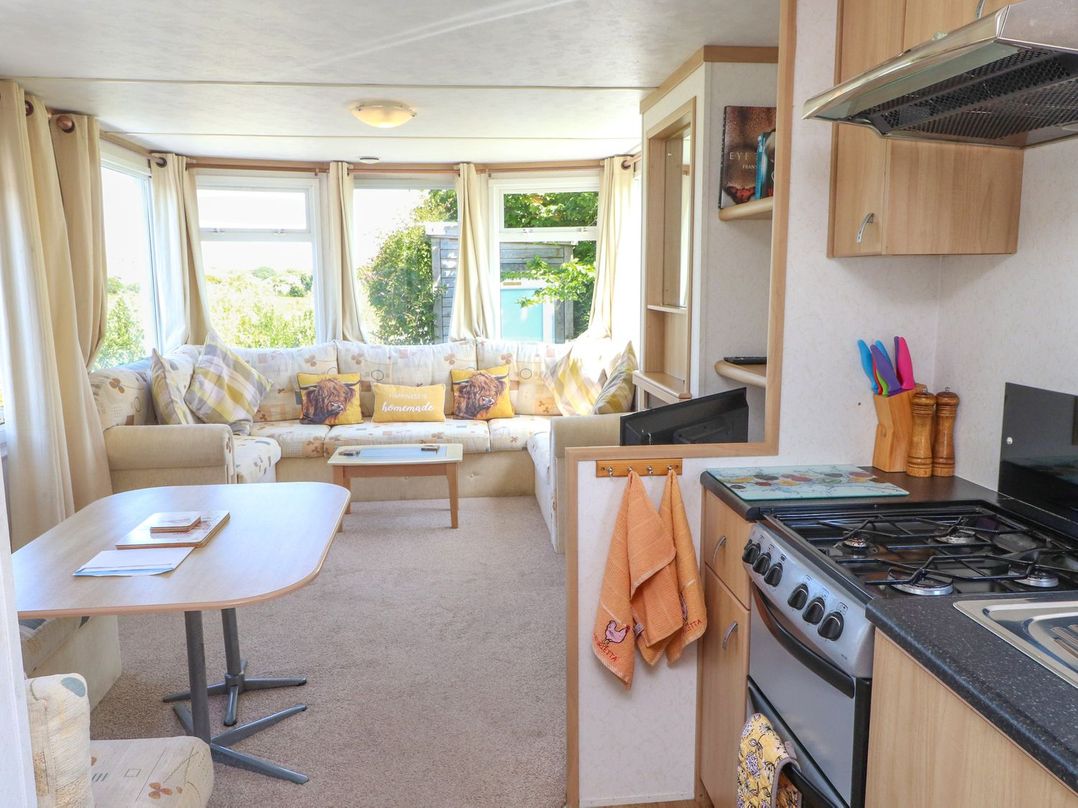 A living room with a sofa and kitchen stove at The Lodge in Amlwch