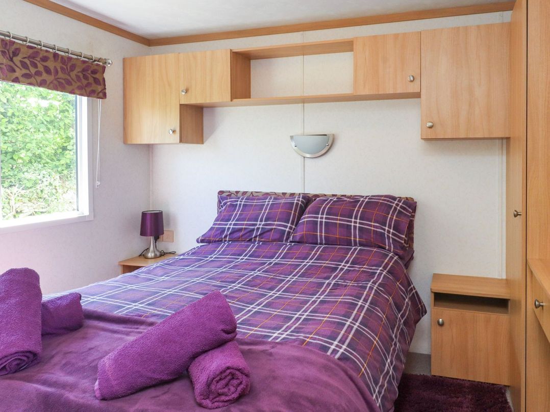 A bedroom with a bed and storage unit at The Lodge Amlwch