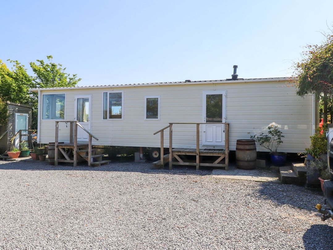 A mobile home with steps and gravel area at The Lodge in Amlwch