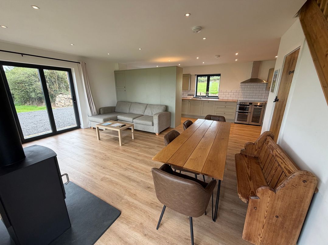 A living room with a dining table and kitchen area at High View Barn in Launceston