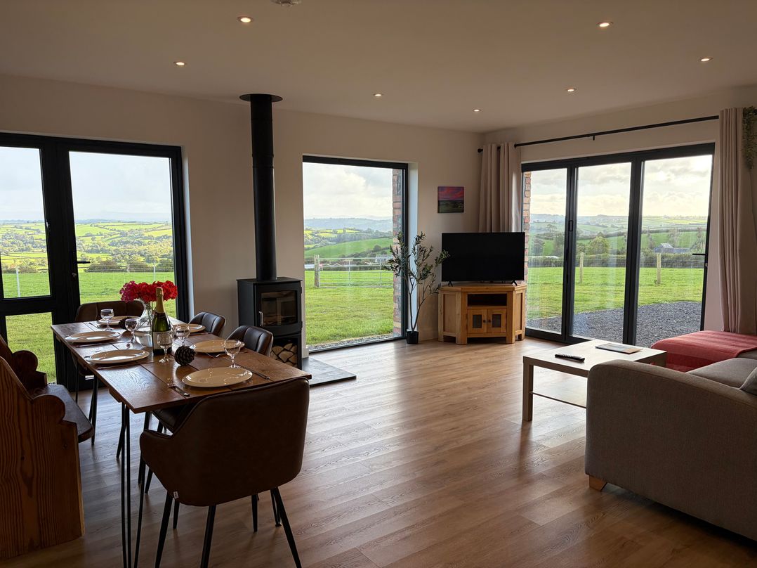 A living room with a dining area and large windows at High View Barn Launceston