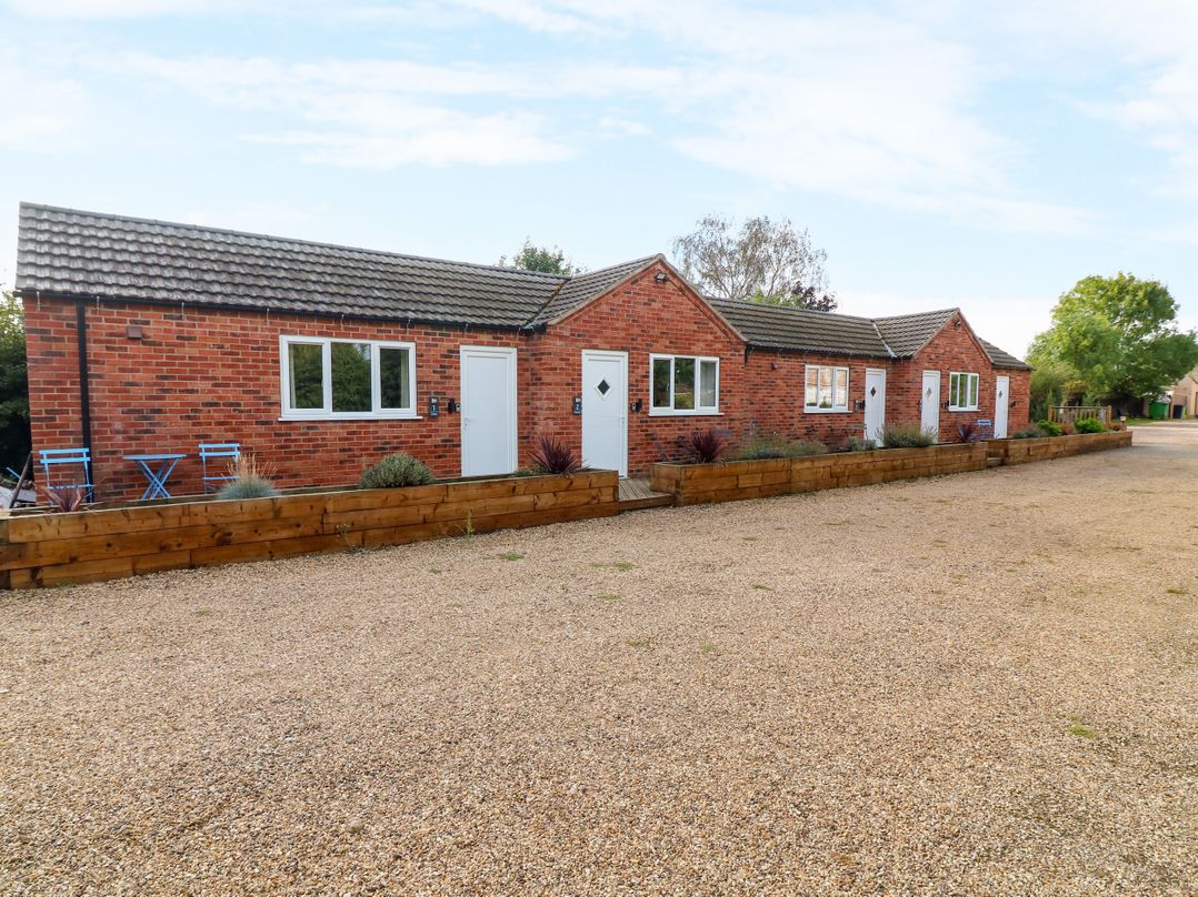 A brick building with multiple units and a gravel driveway at Walcott Lodges - Catley in Billinghay, Lincolnshire