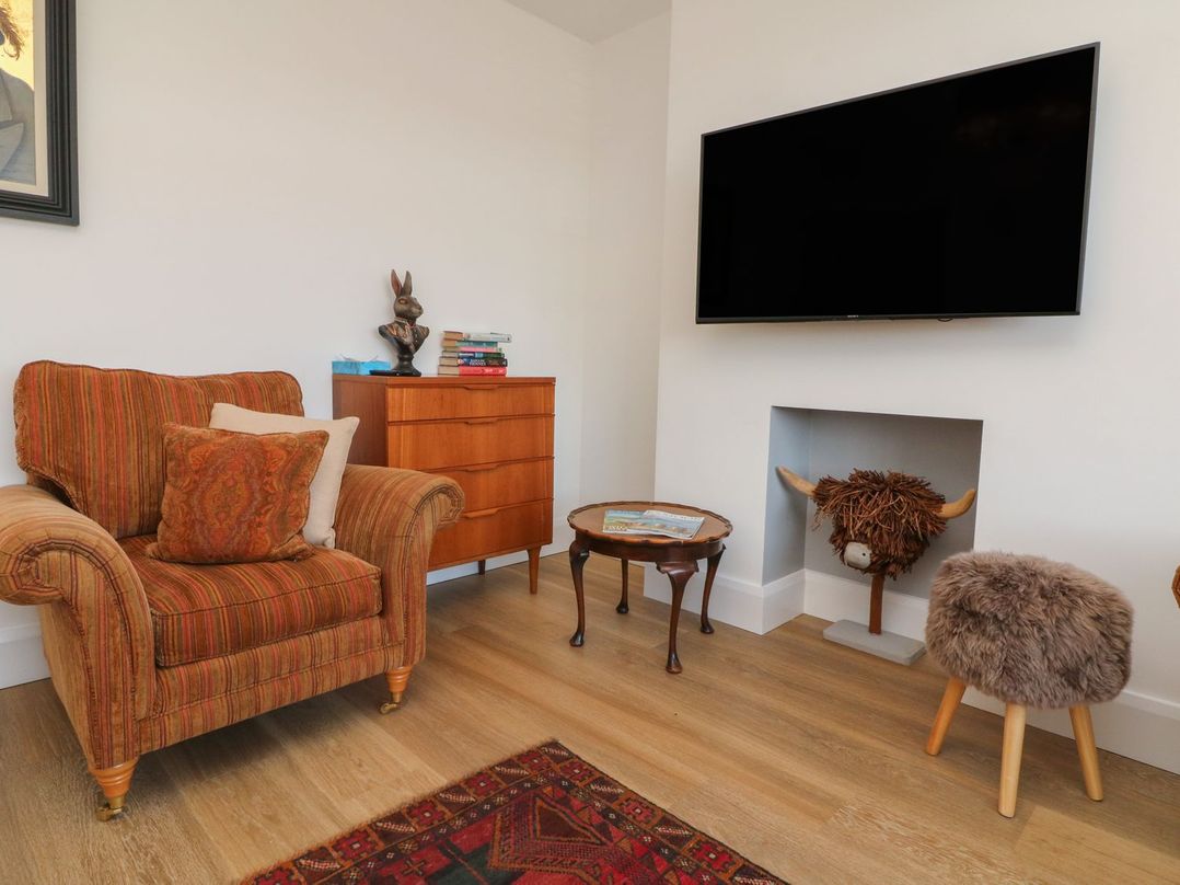 A living room with an armchair and a television at Wendy's Cottage in Minehead