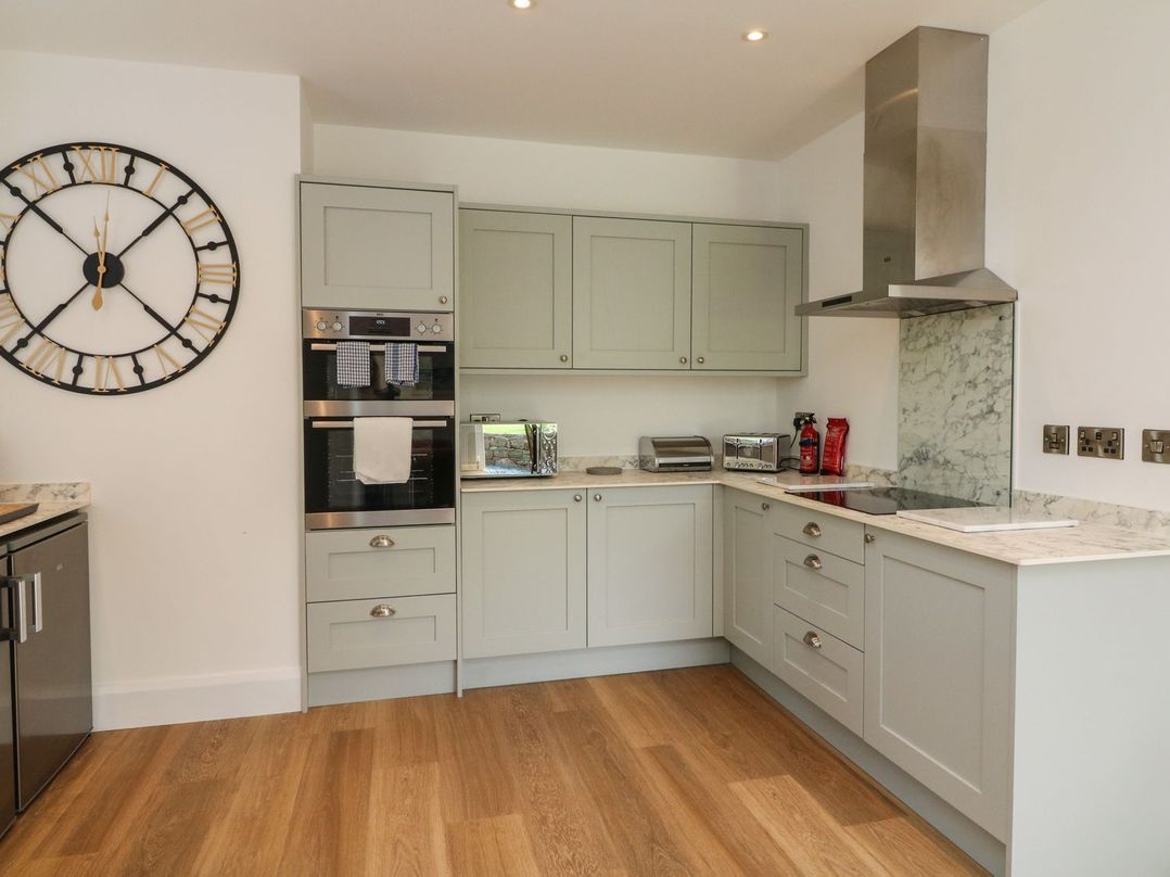 A kitchen with cabinets and appliances at Wendy's Cottage in Minehead