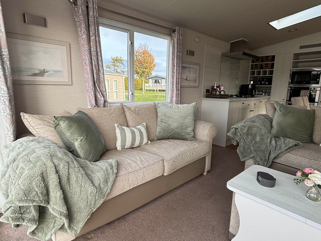 A living room with a sofa and kitchen area at Primrose Valley Park - Pebbles Retreat in Primrose Valley