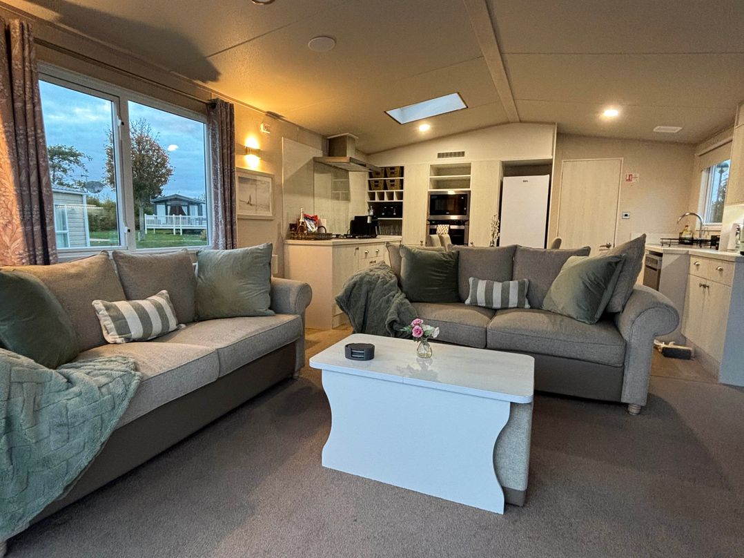 A living room with a sofa and kitchen area at Primrose Valley Park - Pebbles Retreat in Primrose Valley