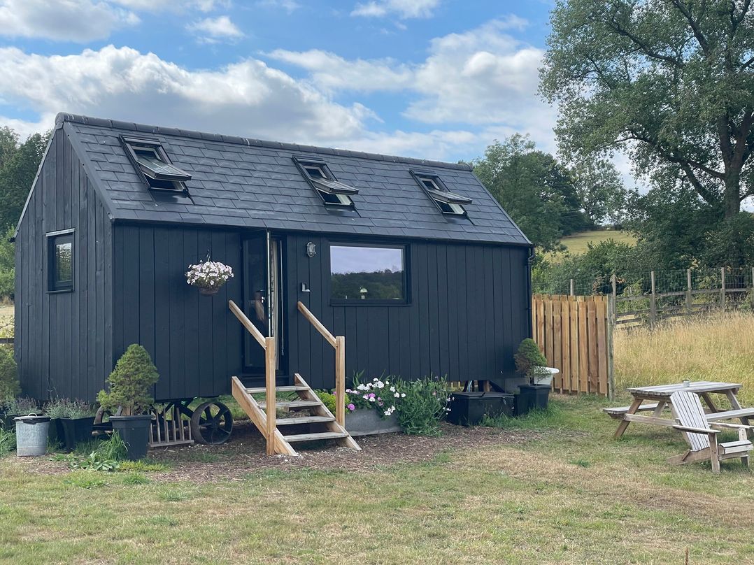 A black house with steps and plants outside at Cloud Cabin in Gillow Heath near Biddulph