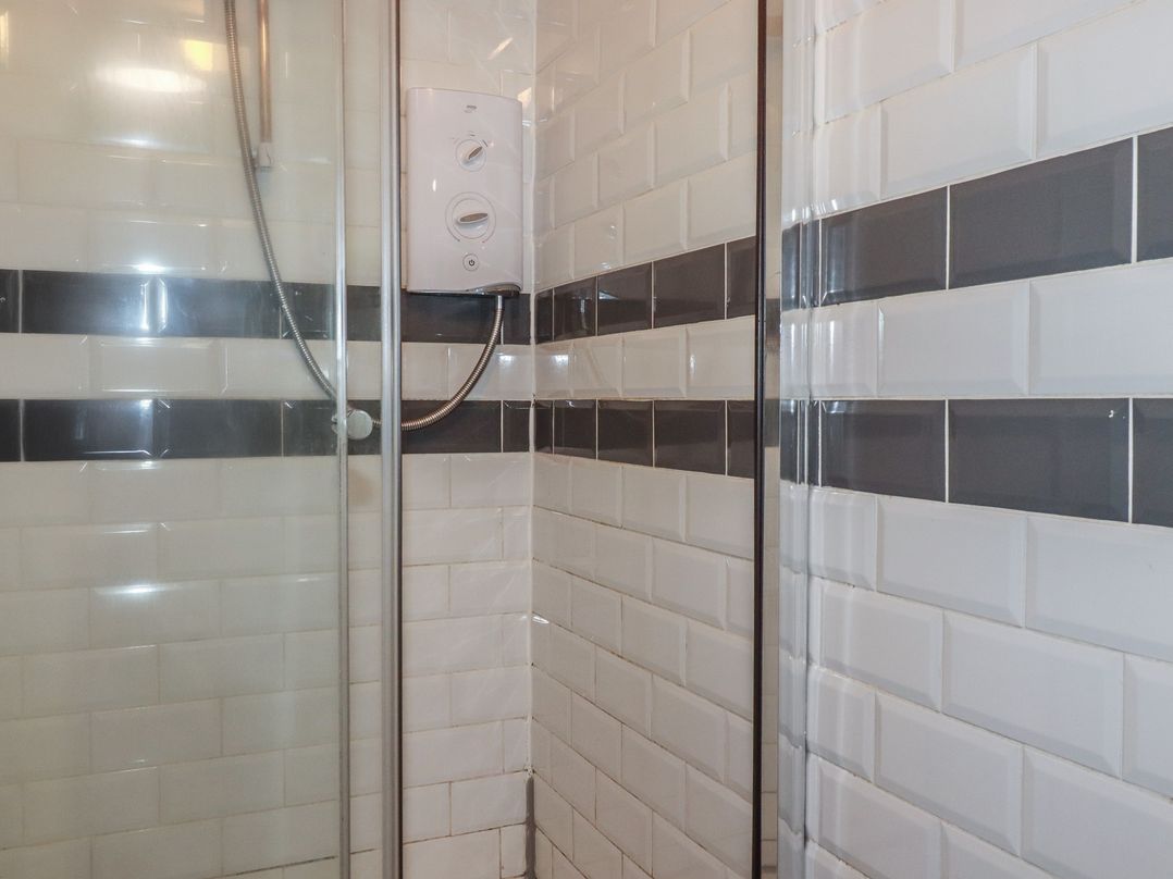 A shower with tiles and controls at Shoreline Apartment No.8 in Newquay