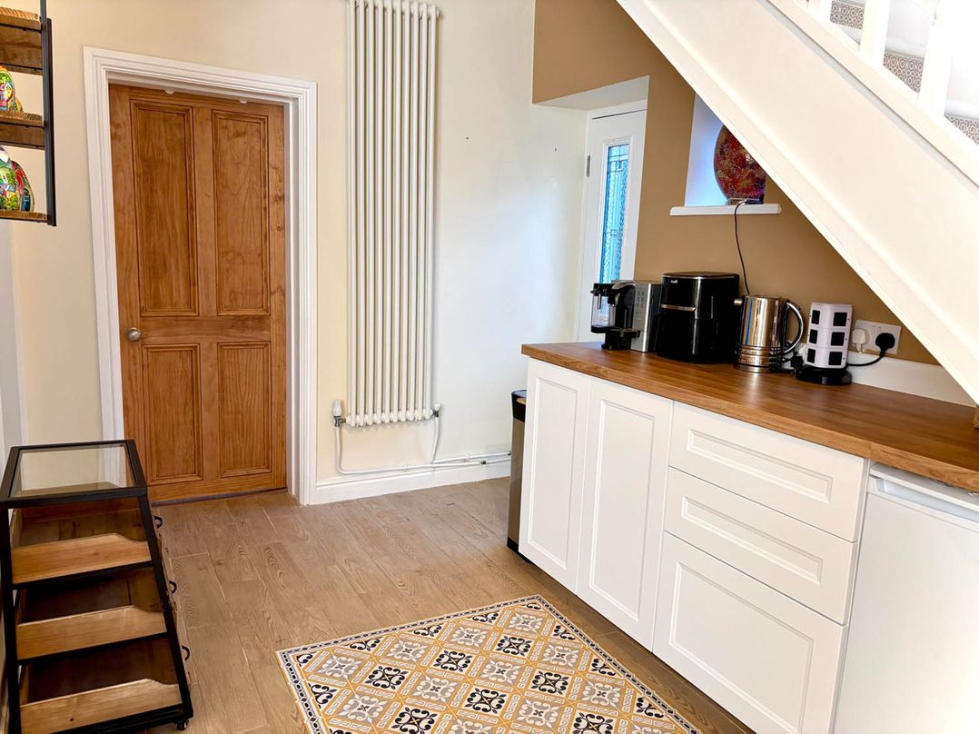 A kitchen with a door, countertop, appliances, and a rug at 5 Guests  2 Bedrooms  Free Parking 1min Beach Llandudno