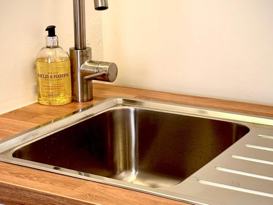A sink with a faucet and hand wash bottle at a kitchen in Llandudno