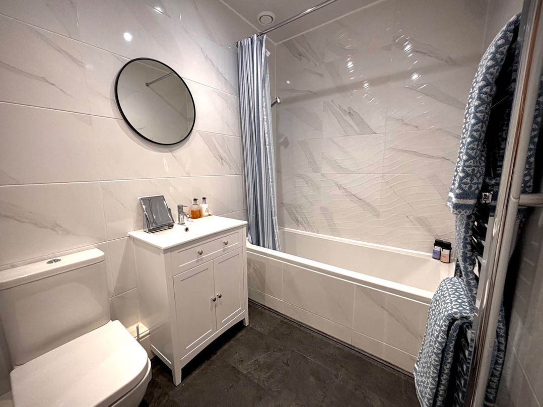 A bathroom with a bathtub, toilet, sink, and mirror at 5 Guests  2 Bedrooms  Free Parking 1min Beach Llandudno