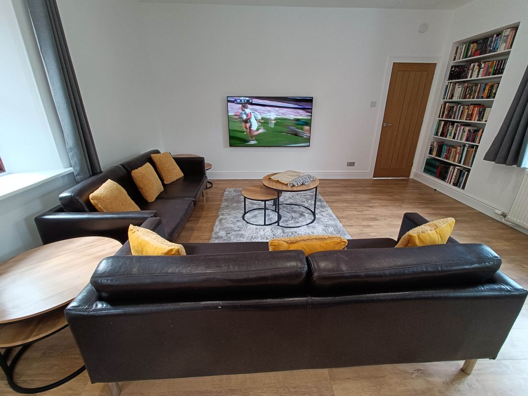 A living room with a television and bookshelves at RnB Rural n Beautiful Near Barrhill