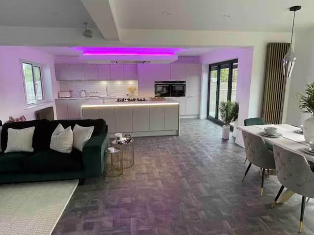 A living room with a sofa and kitchen units at Hot tub  BBQ  Garden Parking  Sleeps 8 Worcester