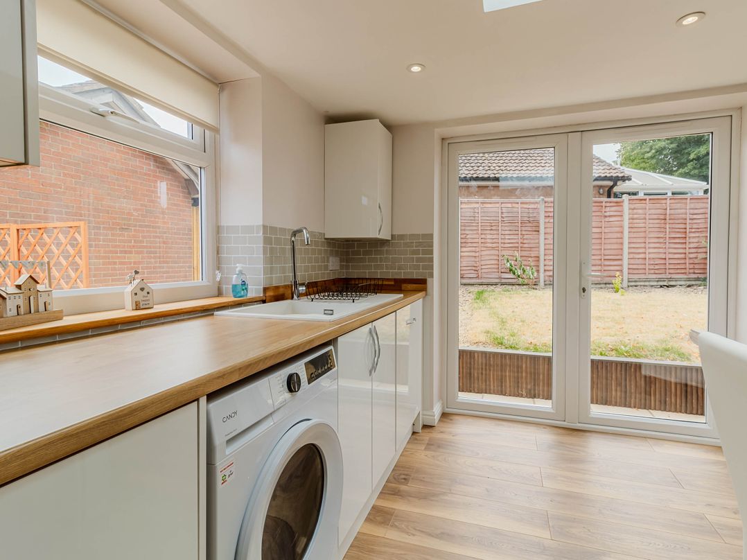 A kitchen with a wash machine and sliding doors at Loughborough Luxe Bungalow Retreat Sleeps 6 in Shepshed