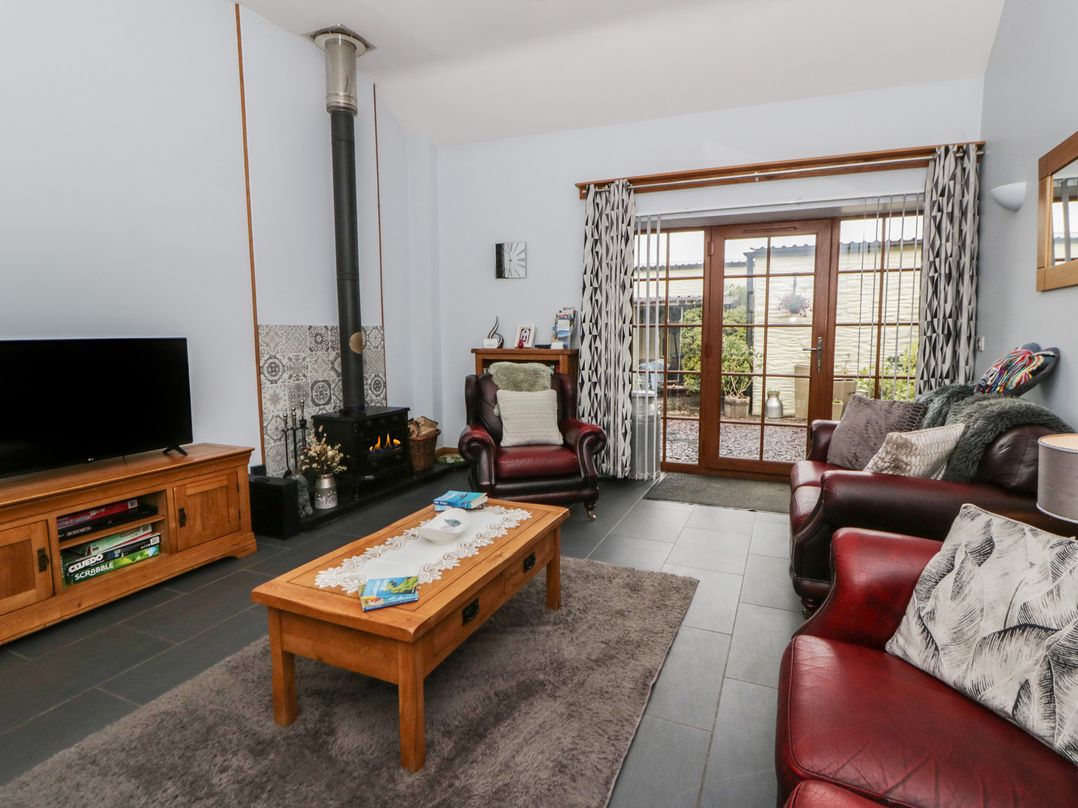 A living room with a fireplace and seating area at Yr Hen Llaethdy near Blaen-Cil-Llech near Newcastle Emlyn