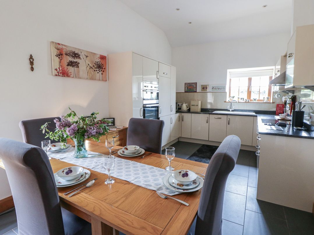 A kitchen with a dining table and chairs and flowers at Yr Hen Llaethdy in Blaen-Cil-Llech near Newcastle Emlyn