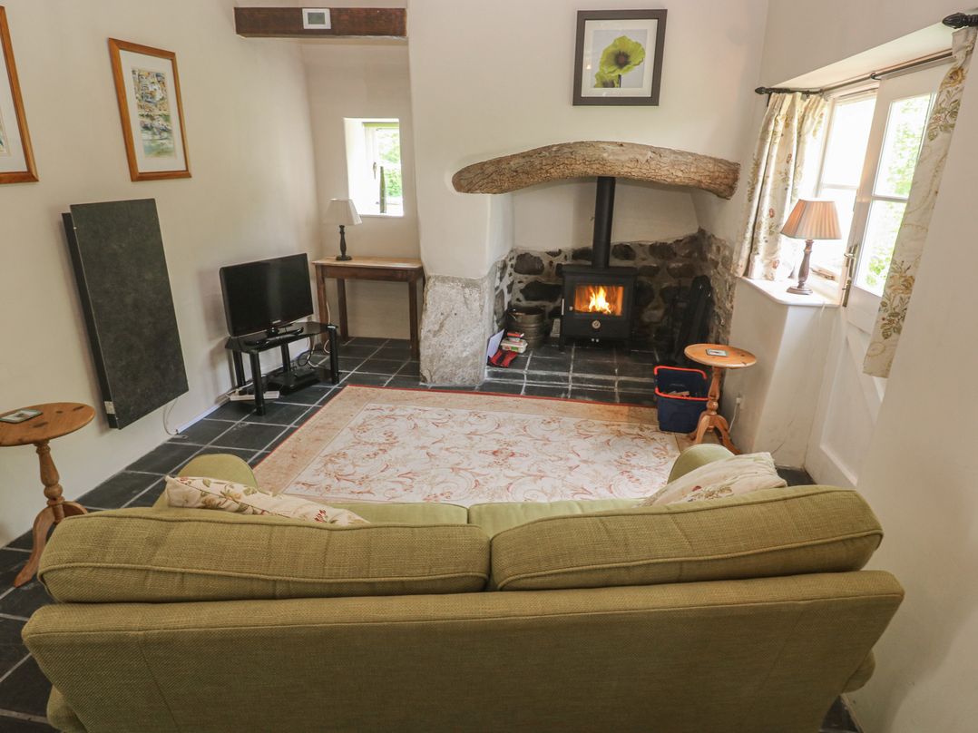 A living room with a wood stove and television at Swallows St Keverne, Lizard Peninsula