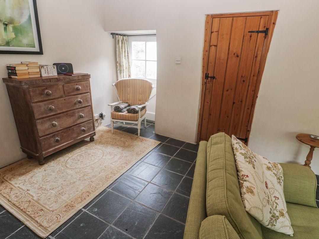 A living room with a chest of drawers, a rocking chair, and a sofa at Swallows St Keverne, Lizard Peninsula