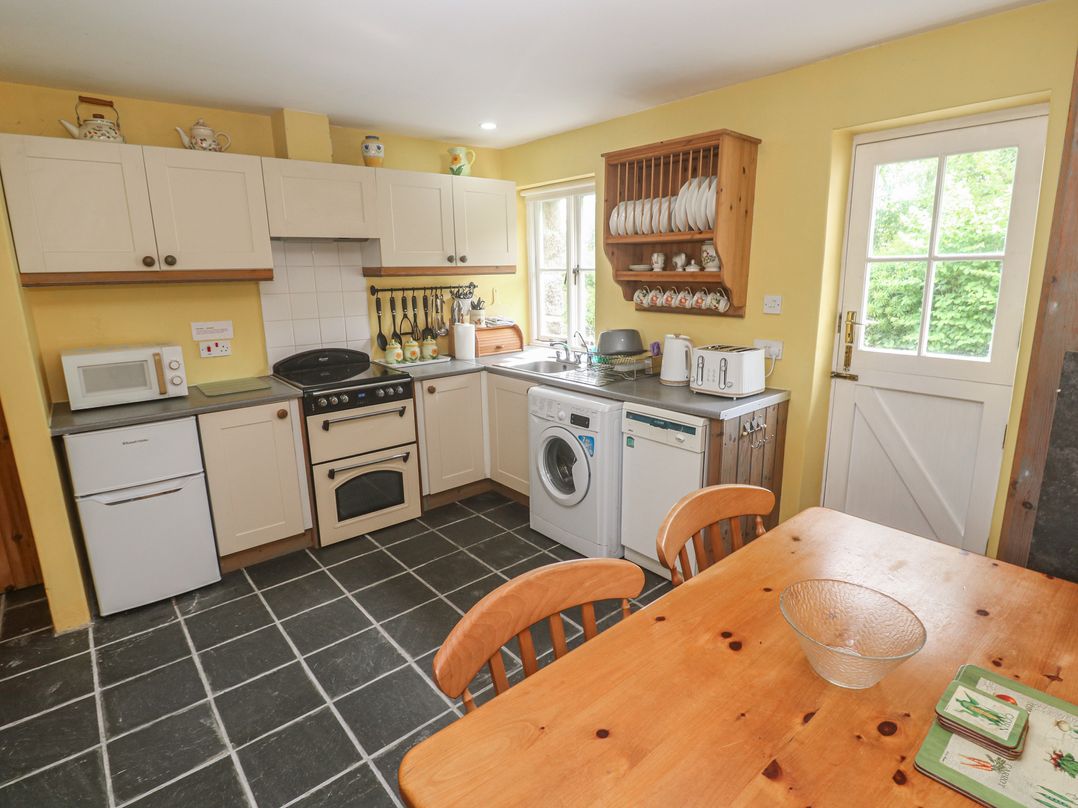 A kitchen with appliances and dining table at Swallows St Keverne Lizard Peninsula