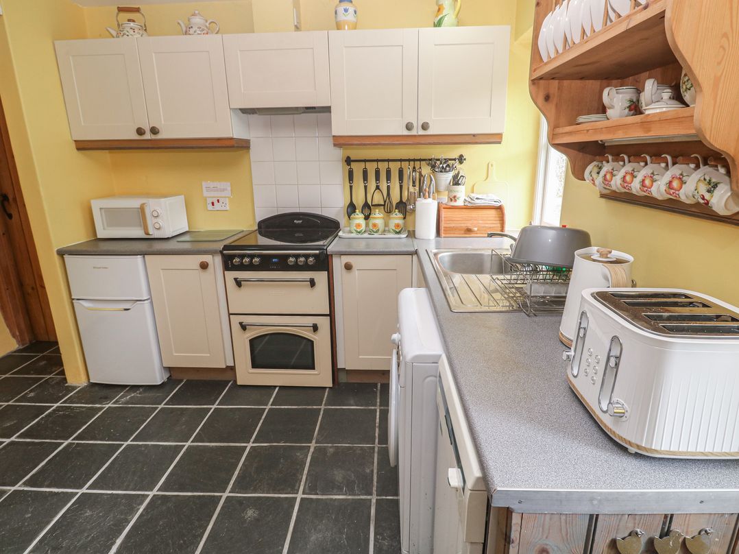 A kitchen with appliances and cabinets at Swallows, St Keverne, Lizard Peninsula