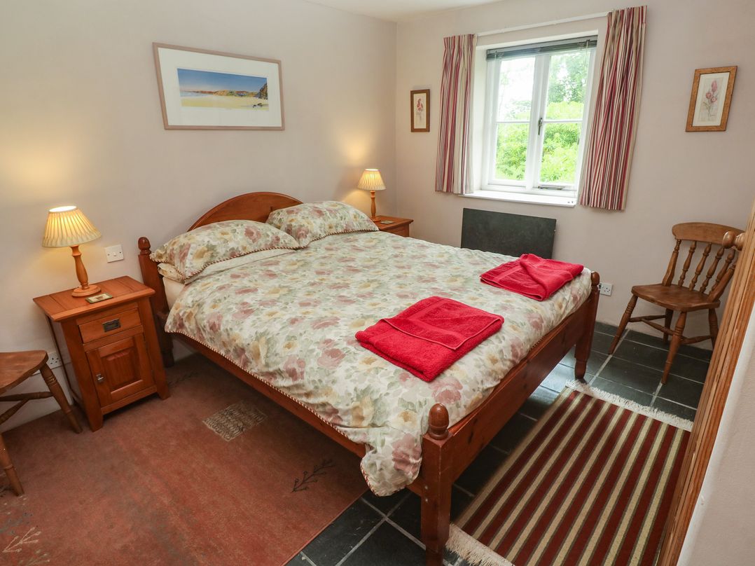 A bedroom with a double bed and two bedside tables at Swallows, St Keverne, Lizard Peninsula