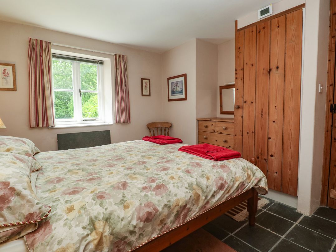 A bedroom with a bed and dresser at Swallows, St Keverne, Lizard Peninsula