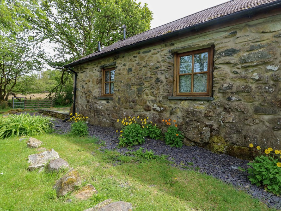 A garden with a stone wall and flowers at Bythyn Ddol Hafod Capel Curig