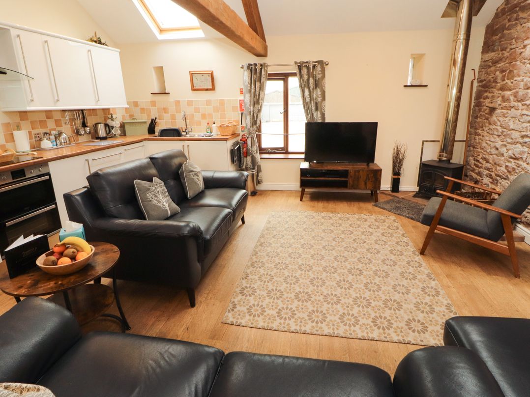A living room with a sofa and kitchen area at Stable Cottage in Bolton Low Houses