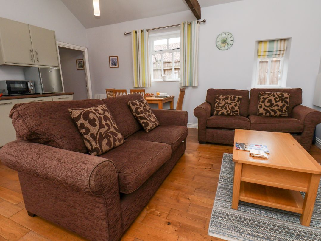 A living room with a sofa and dining area at Beacon in Gerrick near Moorsholm