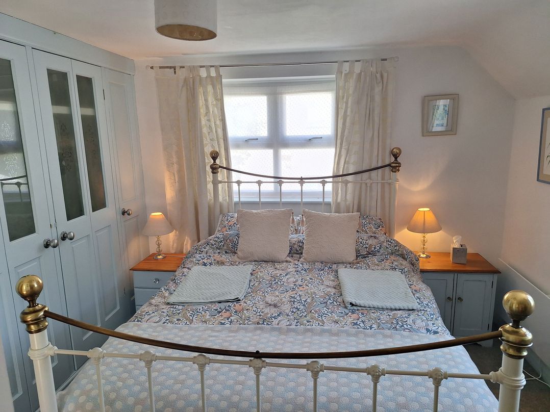 A bedroom with a bed, wardrobe, and lamp at Wood Glen Cottage in Rushlake Green near Heathfield