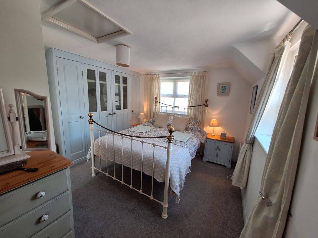 A bedroom with a bed and wardrobe at Wood Glen Cottage in Rushlake Green near Heathfield