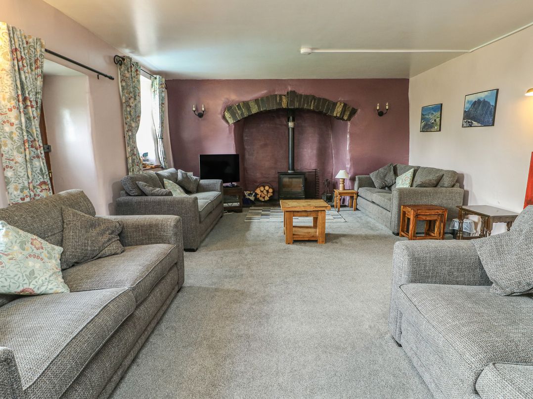 A living room with a fireplace and sofas at Glan y Gors in Dinorwic near Llanberis