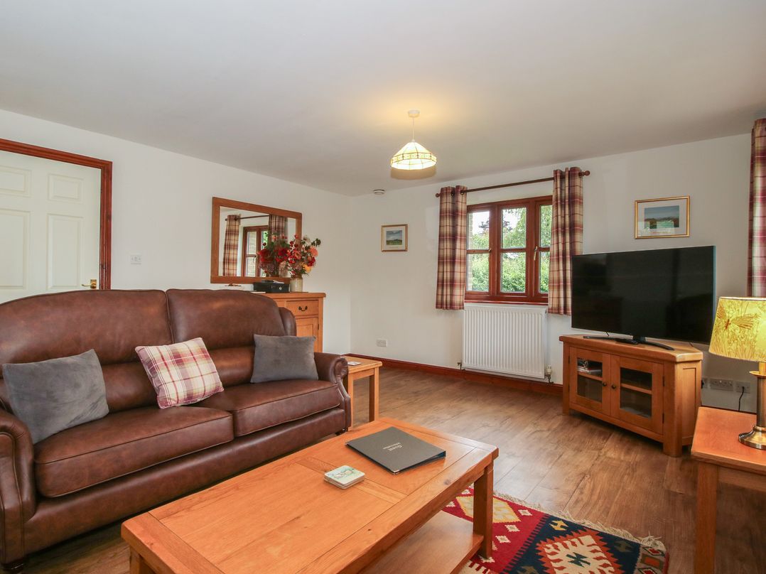 A living room with a sofa and television at Byne Brook Cottage Strefford near Craven Arms