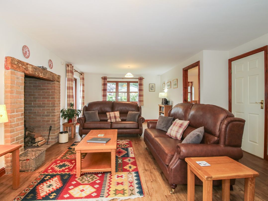A living room with sofas and a fireplace at Byne Brook Cottage in Strefford near Craven Arms