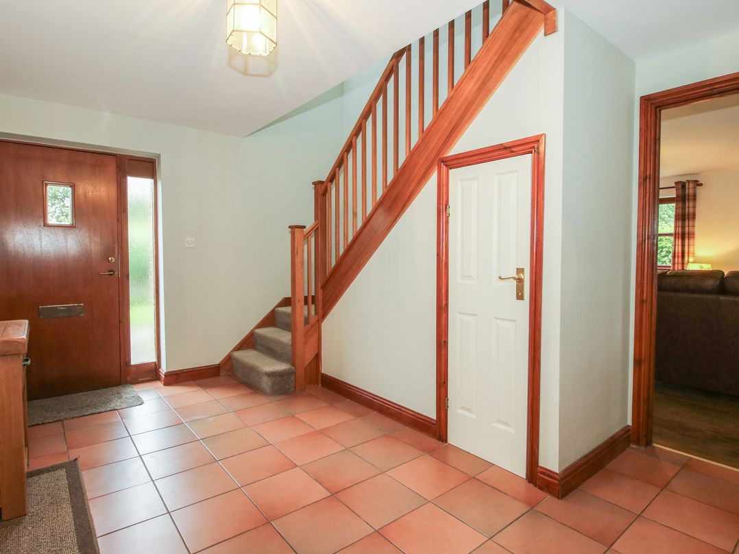 A hallway with a staircase and front door at Byne Brook Cottage in Strefford near Craven Arms