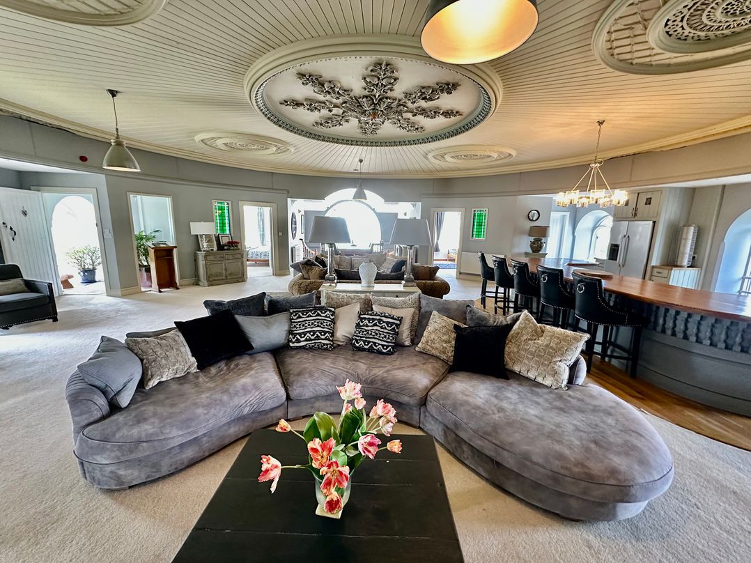 A living room with a large sofa and a bar counter at Capel Mawr in Llanrug near Llanberis