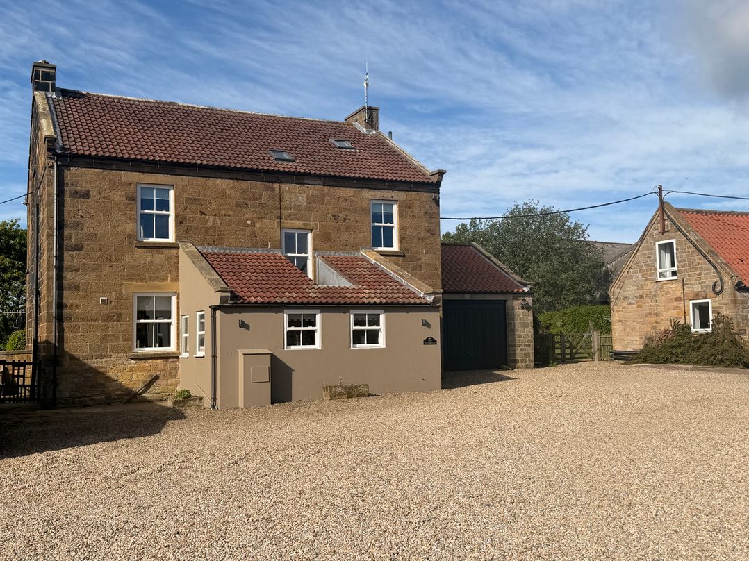 A house with a garage and gravel driveway at The Farmhouse in Boggle Hole near Robin Hood's Bay