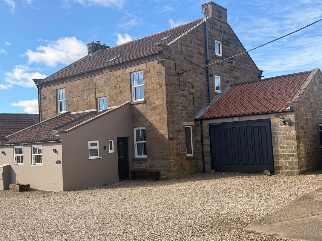 A house with a garage and gravel driveway at The Farmhouse in Boggle Hole near Robin Hood's Bay