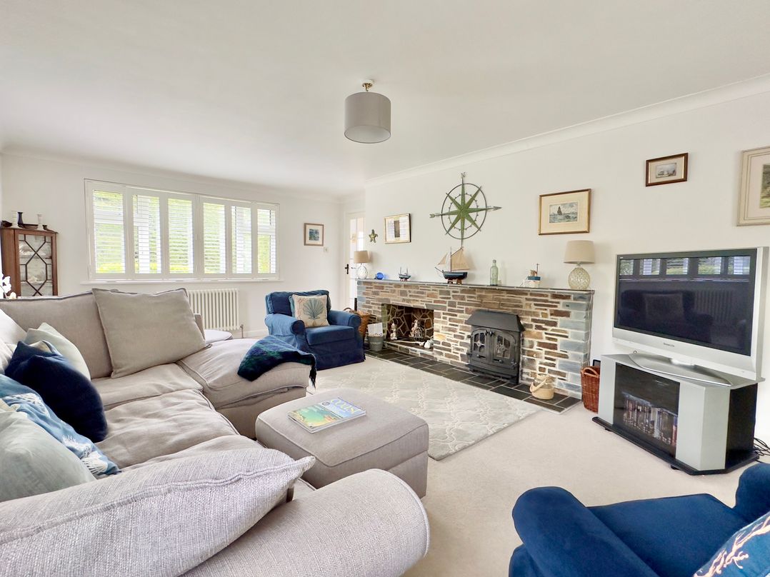 A living room with a fireplace and seating at Kilcarreg in Rock near Wadebridge
