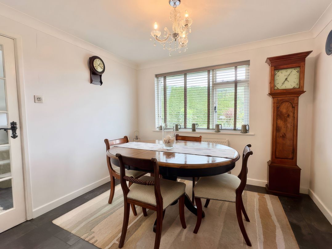 A dining room with a round table and clocks at Kilcarreg in Rock near Wadebridge