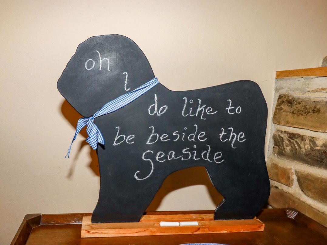 A chalkboard shaped like a dog with a ribbon and text at 4 Mowhay Cottages, Gorran Haven