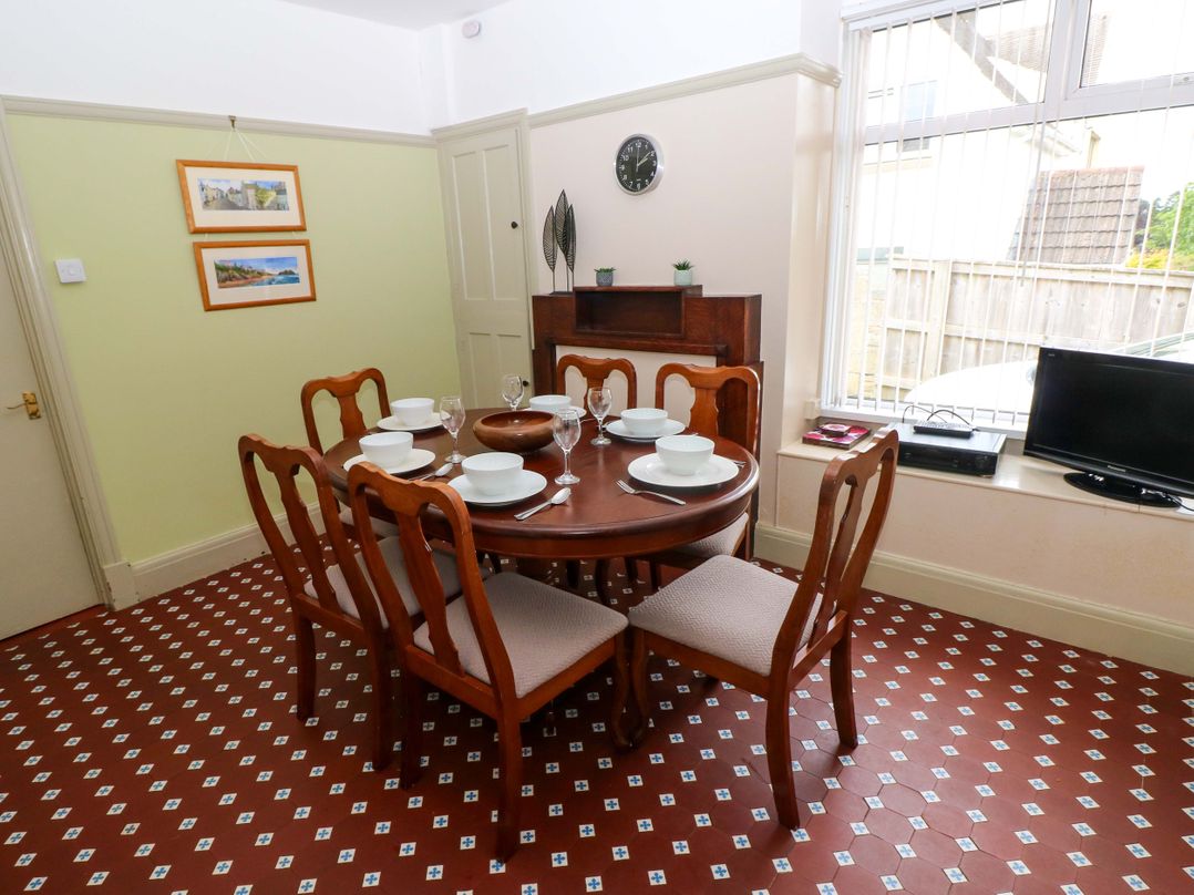 A dining room with a table set for six at White Thorns in Haverfordwest