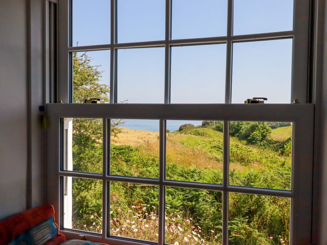 A view from a window overlooking grass and sea at Penrose Farm Cottage St Keverne
