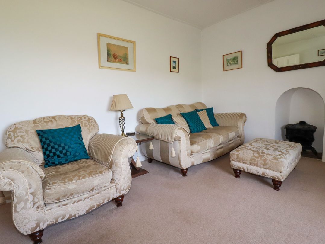 A living room with a sofa, armchairs and footstool at Penrose Farm Cottage St Keverne